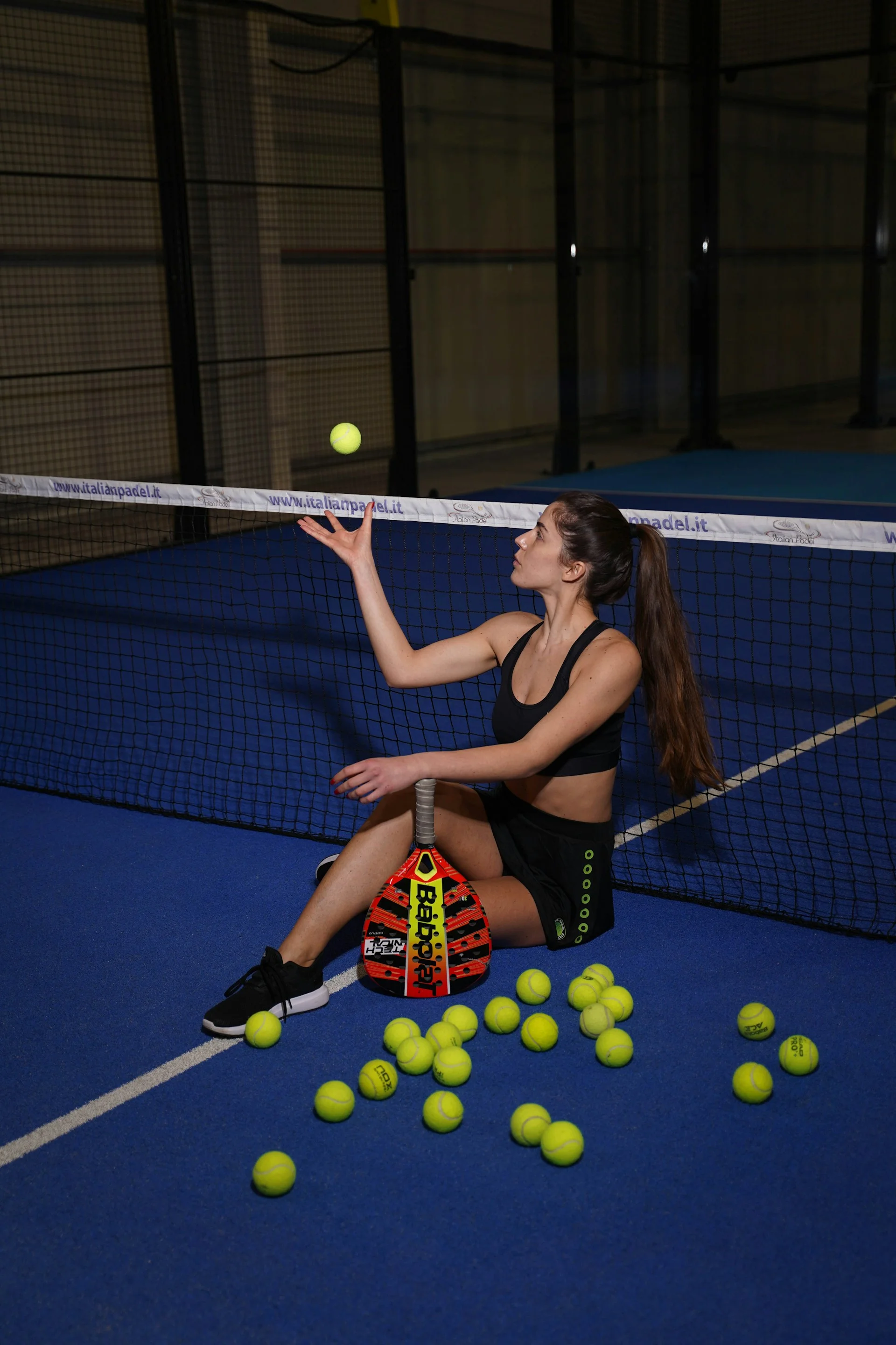 Beginner padel player with racket and balls on court