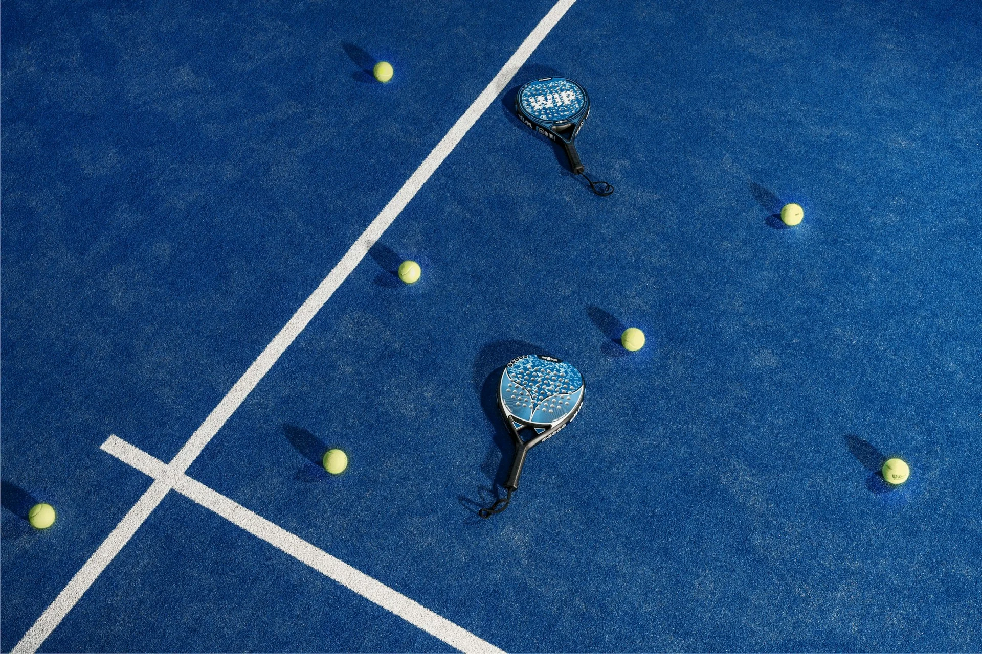 Padel rackets and balls on a blue court