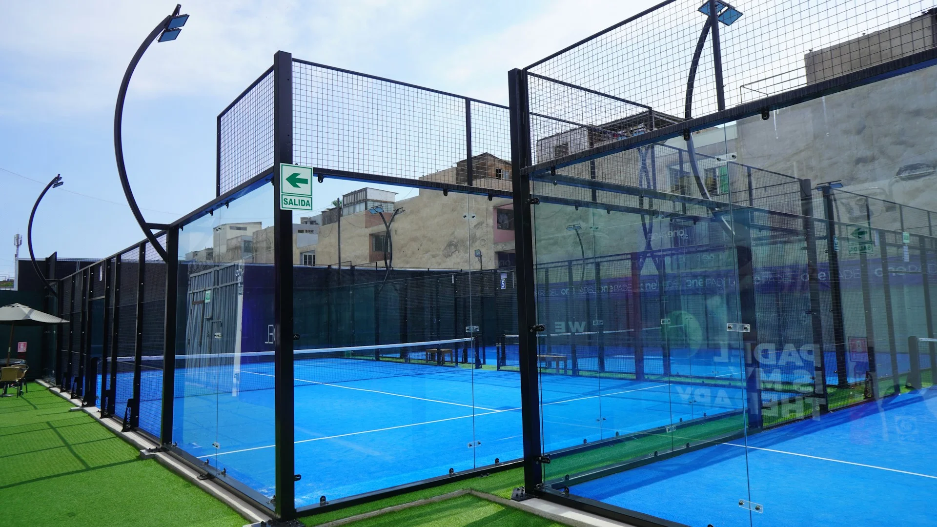 Campo de padel fechado com paredes de vidro e vedação metálica