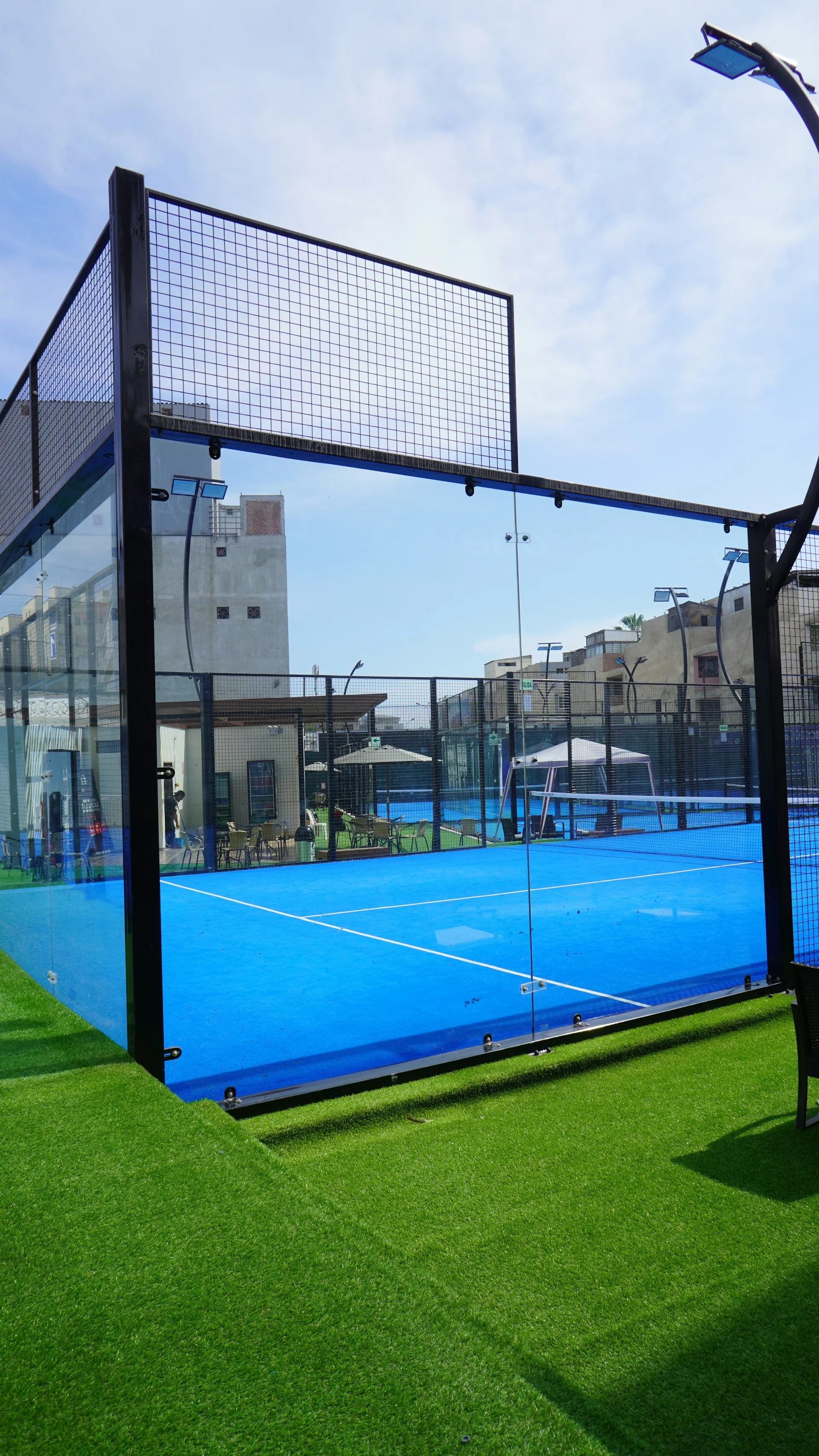 Campo de padel com rede e paredes de vidro — vista interior
