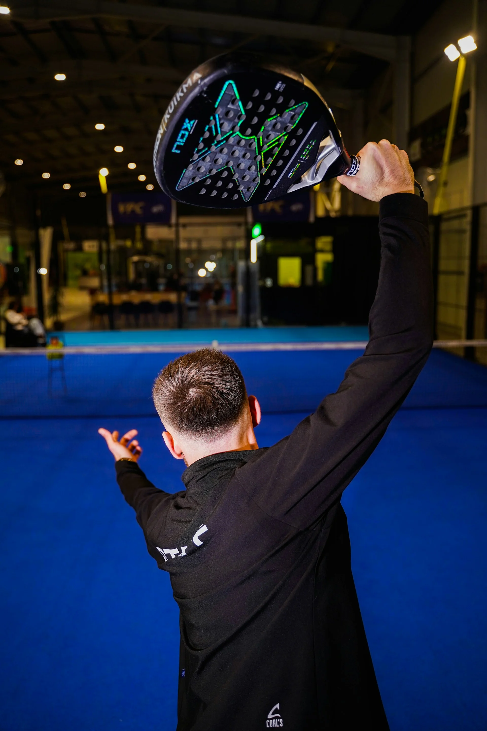Padel player raising racket for an overhead shot