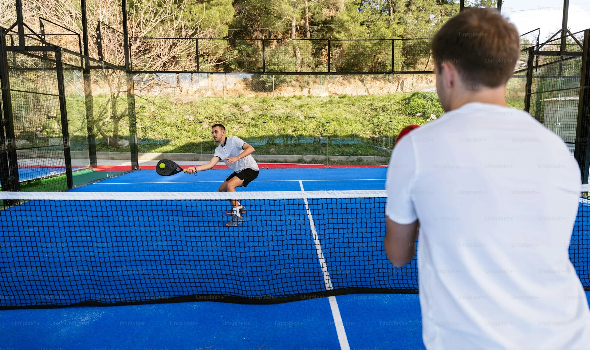 Two players on a padel court demonstrating doubles positioning
